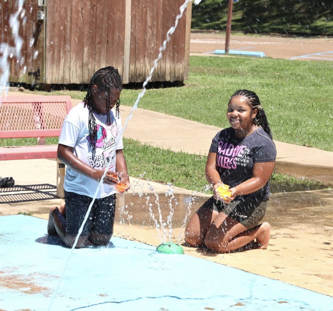 Two kids playing on a splash pad.
